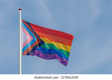 Celebration of pride month new rainbow flag on the pole and waving in the air with blue sky as background, Symbol of Gay, Lesbian, Bisexual and Transgender, LGBT community, Worldwide social movements.