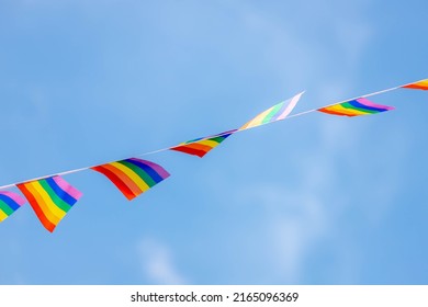 Celebration Of Pride Month, Waving Small Colourful Flags Hanging On The Rope With Blue Sky, The Rainbow Flag Is A Symbol Of Lesbian, Gay, Bisexual, Transgender (LGBT) And Queer, LGBT Social Movements.