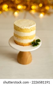 Celebration - a small cake on a stand against a background of golden decor - Shutterstock ID 2226581191