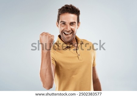 Celebration, smile and winner with portrait of man in studio on white background for bonus or success. Achievement, fist and motivation with happy person cheering yes for bonus, goal or target