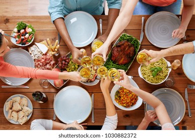 Celebration, Thanksgiving Day, Eating And Holidays Concept - Group Of People Having Dinner At Table With Food And Clinking Wine Glasses