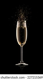 Celebration theme. Glass of champagne with splash, isolated on black background