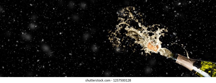 Celebration theme with splashing champagne on black background with snow and free space. Christmas or New Year, Valentines day background.
