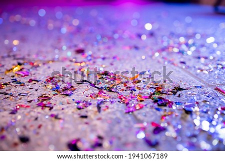 Celebratory confetti are scattered on the floor, the background is blurred