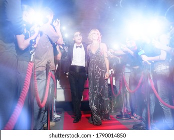 Promi-Ehepaar bei einer Premiere mit Paparazzi-Kameras und Blitzen