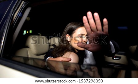 Celebrity couple in car hiding with hand from magazine photographers cameras