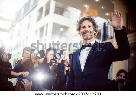 Celebrity waving to paparazzi photographers at event