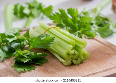 Celery stems and leaves on wooden cutting board - Shutterstock ID 2116408211