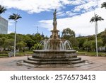 Celestial Fountain built in 1885 in centre of Coconut Place in the Central Gardens surrounded by trees and blue sky, Noumea, Grande Terre Island, New Caledonia