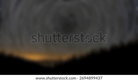 Celestial light trails curve concentrically above a silhouetted forest landscape at night