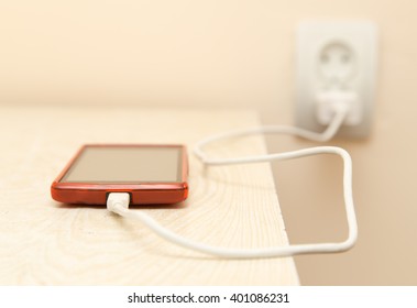 cell phone is being charged from the electrical outlet