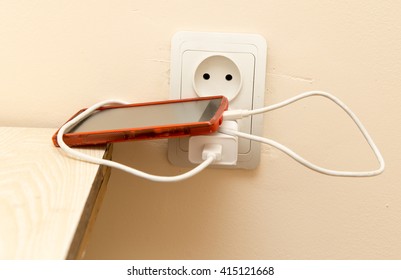 cell phone is being charged from the electrical outlet
