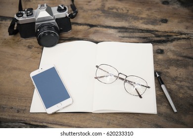 cell phone, diary and old camera on a wooden table