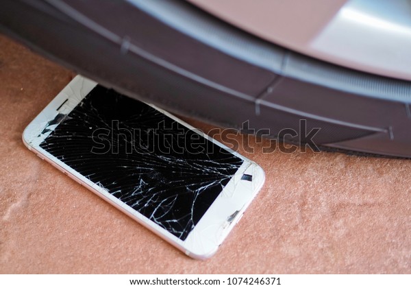 cell phone falls on\
floor under car wheel. Broken screen glass. Accidents cause\
smartphone damage.