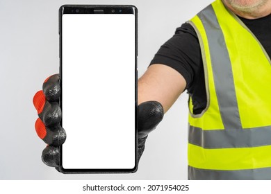 Cell phone hand builder. Human shows phone. Builder in yellow vest. Smartphone mockup with empty space. Place for text on phone screen. Cellphone for advertising construction applications.