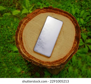 cell phone lies on the old a tree stump the summer in a garden. Mobile phone against brown dry new stump, Mobilephone. black empty screen. mock up. - Powered by Shutterstock