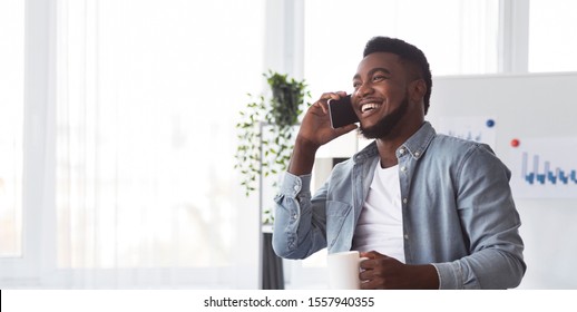 Cell Phones At Work Concept. African american employee calling to friends during working hours and drinking coffee in office - Powered by Shutterstock