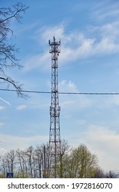 A Cell Tower Against A Pale Blue Cloudy Sky.