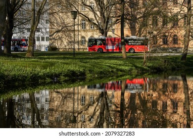 Celle, Germany - April 24, 2021: a bus covered with an advertisement of the savings bank drives past an annex of the Higher Regional Court and is reflected in the water of a moat in the castle park