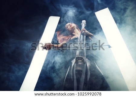 The cellist girl performs on stage. Stage light.