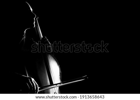 Cello classical music cellist player. Cellist with musical instrument in darkness