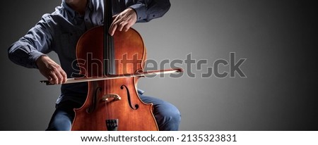Cello player or cellist performing in an orchestra background isolated with copy space