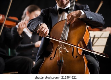 Cello Professional Player With Symphony Orchestra Performing In Concert On Background.