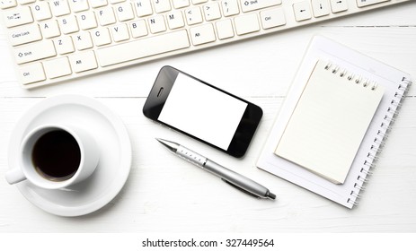 cellphone with computer and coffee cup over white table