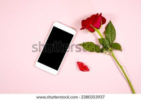 Cellphone mobile phone eVite eCard mockup. Valentine's day wedding love theme styled with a single red rose and lipstick kiss chocolate against a pale blush pink background.