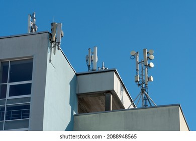 a cellular communication antenna installed on the roof of a high-rise building against a blue sky background. 5G radio network telecommunication equipment with radio modules and smart antennas