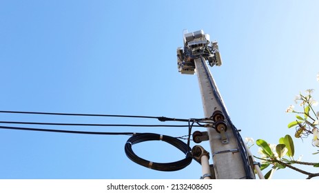Cellular mobile base station. Mobile phone transceiver in 4G and 5G wireless communication system on concrete tower with cables in bottom view on blue sky background with copy space. Selected focus