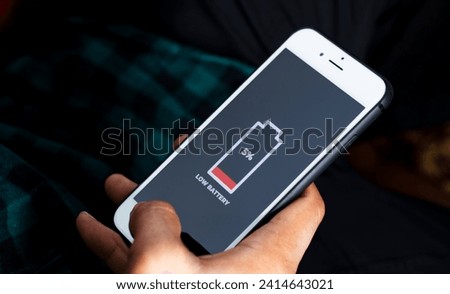 Cellular Problems and Energy Concepts. Close up of Male hand holding a smart phone with sign low battery icon on screen. 