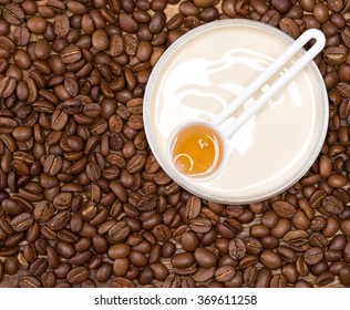 Cellulite busting product concept. Anti-cellulite cosmetics with caffeine. Jar of cream with a spoon of coffee essential oil surrounded by coffee beans. Close-up. Top view. Copy space
