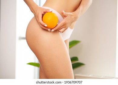 Cellulite problem concept, young woman holding orange near her leg - Shutterstock ID 1936709707