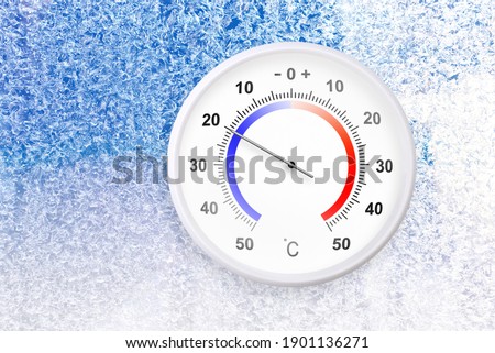 Celsius scale thermometer on a frozen window shows minus 20 degrees 