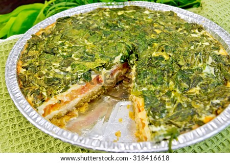 Celtic cake with spinach, tomatoes, oatmeal and eggs in baking dish from a foil on a green napkin
