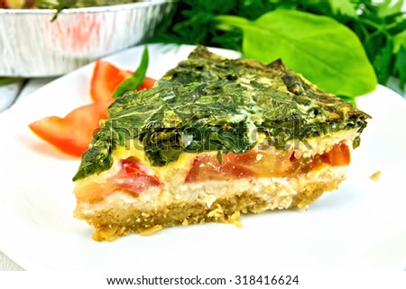 Celtic cake with spinach, tomatoes, oatmeal and eggs in a white plate and baking dish from a foil on a wooden boards background