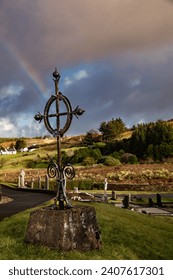 celtic cross in cemetery donegal ireland with rainbow infront of mount errigal