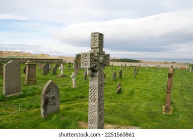Celtic cross headstone in an old graveyard at St Aidan's Church - Shutterstock ID 2251563861
