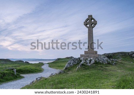A Celtic cross on Llanddwyn, along the coast of Anglesey, Wales, near Newborough Beach. It is sunset