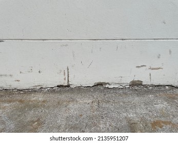 The cement floor collapsed and saw the crevices into the hollow under the building. White black grey wall with cracks, texture background