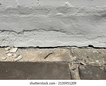 The cement floor collapsed and saw the crevices into the hollow under the building. White black grey wall with cracks, texture background