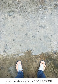 Cement Floor That Is Wet With 2 Feet That Walk Through The Rain