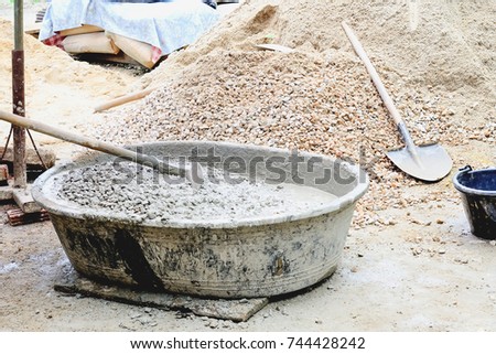 Cement is mixed with sand and rock by workers.