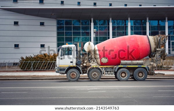 Cement mixer truck delivering concrete to\
construction site. Concrete mixer delivers concrete, truck moving\
on city road. Mixer truck transporting cement. Heavy machinery\
deliver cement