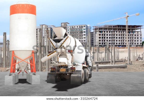 Cement mixer truck parked in\
front of a new building under construction with precast concrete\
piles