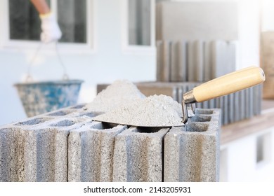 Cement or mortar, Cement powder with a trowel put on the brick for construction work and there are construction workers in the background.