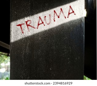 Cement post with handwriting text Trauma -  person's emotional response to a distressing experience,  lasting emotional response results from intensely stressful  events