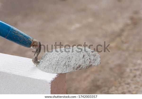 Cement powder or mortar with \
trowel put on the Lightweight Concrete brick for construction\
work.\
