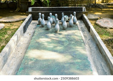 Cement toy bowling with skittles for decoration on lawn games in garden or yard. Outdoor bowling alley with bowling balls and pins made of decorative concrete for relaxing in park. Selective focus. - Powered by Shutterstock